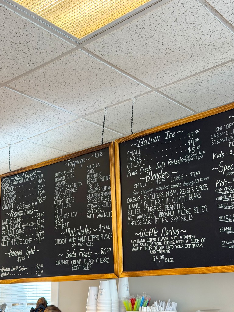 Chalkboard menu listing hand-dipped flavors, sundaes, shakes, and toppings