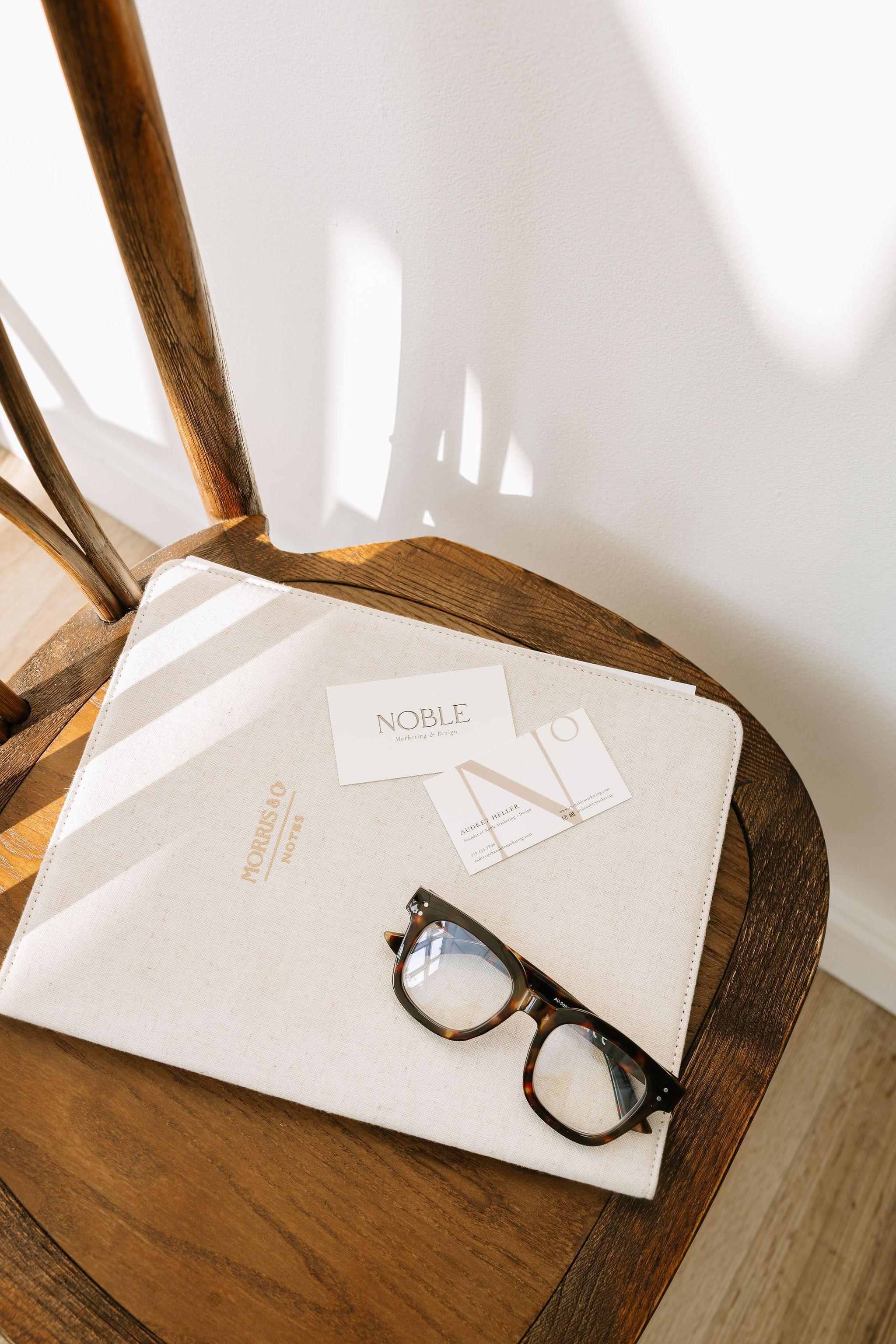 Overhead view of hands on printed branding proofs and mood boards on a light wood table.