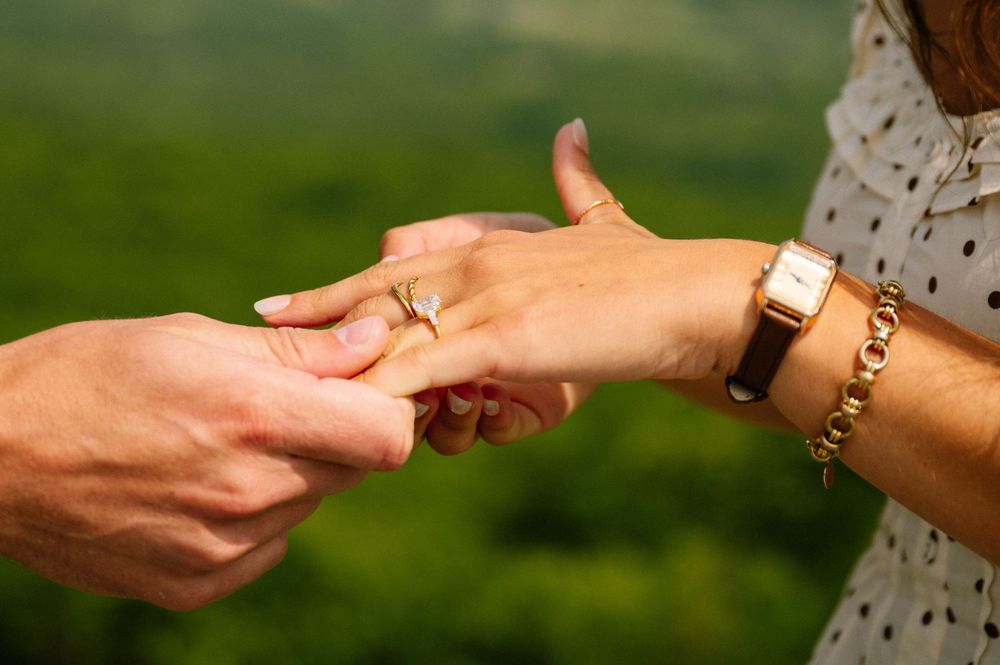Close-up of hands and an engagement ring against a soft green background