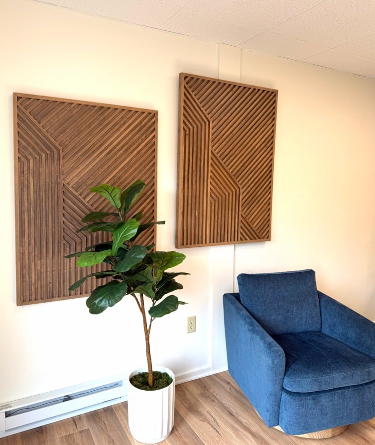 Hatchworks lounge with blue armchair, geometric wood wall art, and fiddle-leaf fig plant