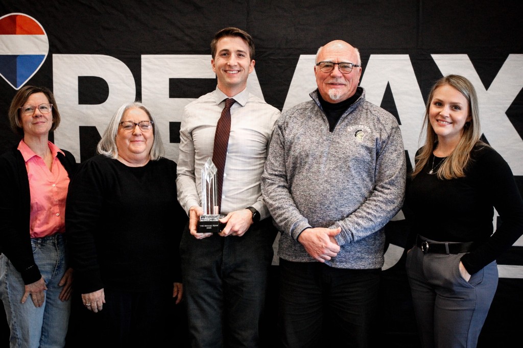 RE/MAX Pinnacle team posing with crystal awards in front of a branded backdrop