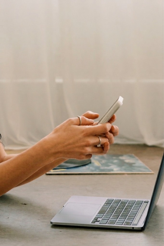 Hands holding a phone beside a laptop on the studio floor